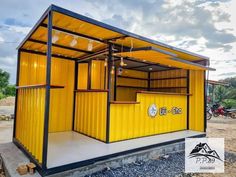 a yellow and black building sitting on the side of a dirt road next to a forest