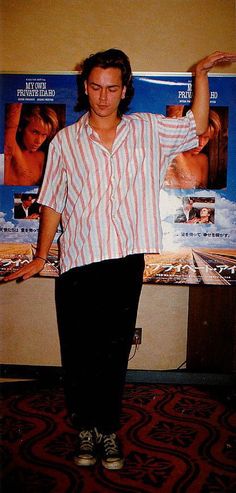 a man standing in front of a movie poster holding his hands up to the side