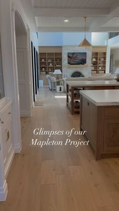 an open kitchen and living room with wood flooring in the center, along with white cabinets