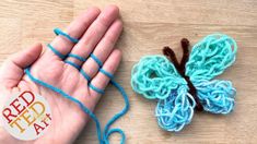 a hand holding yarn next to a crocheted butterfly