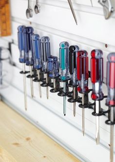 there are many different types of screwdrivers on the pegs attached to the wall