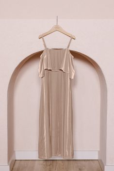 a dress hanging on a hanger in front of a wall with arched doorways