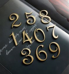 the numbers are written in cursive gold on a black surface with writing underneath