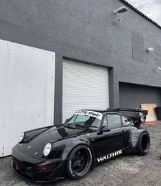 a black porsche parked in front of a garage