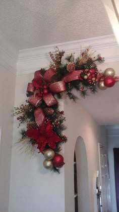 a christmas wreath hanging on the wall in a room with white walls and red decorations