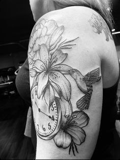 a black and white photo of a woman's arm with flowers on the clock