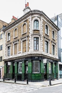 an old brick building with green shutters on the corner