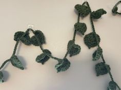 green crocheted flowers hang from hooks on the wall