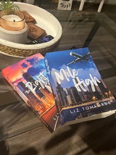 two books sitting on top of a glass table next to a bowl with a plant