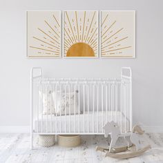 a white crib with two paintings on the wall and a rocking horse next to it