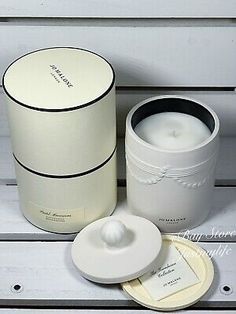 an empty white candle next to a round box