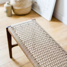 a woven bench sitting on top of a hard wood floor