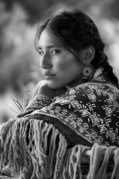 a black and white photo of a woman wearing a shawl with her hand on her shoulder