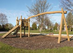 a wooden swing set in the middle of a park