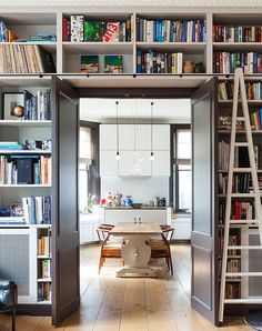 a living room filled with furniture and bookshelves next to a dining room table