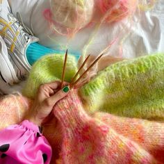 someone is knitting yarn with needles on the bed