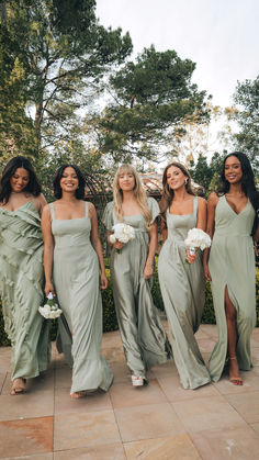 four bridesmaids in sage green gowns posing for a photo at their wedding