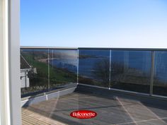 an empty tennis court in front of a large window with the view of water outside