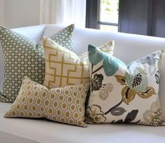 four pillows sitting on top of a white couch