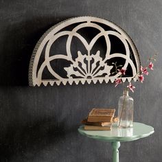 a small table with a vase and book on it next to a wall mounted shelf