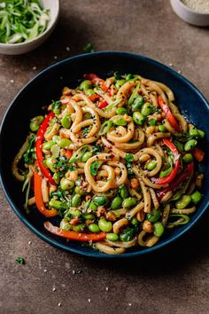 a blue bowl filled with noodles and vegetables