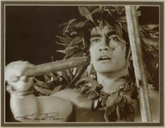 an old photo of a man holding a stick in his hand and wearing a headdress