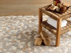 a wicker table with towels and bottles on it next to a tiled floor in a bathroom