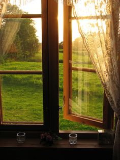 an open window with the sun shining through it and two cups in front of them