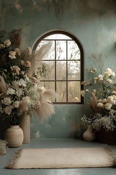 a room with flowers and plants in vases next to a rug on the floor