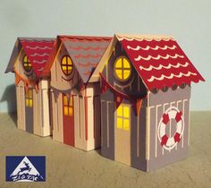 three paper houses with red roofs and lights on top of the roof are sitting in front of a blue wall