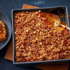 a casserole dish filled with granola next to two plates of food on a table