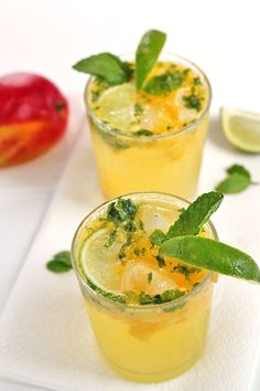 two glasses filled with drinks sitting on top of a white napkin next to an orange slice