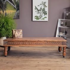 a wooden table sitting on top of a hard wood floor next to a potted plant