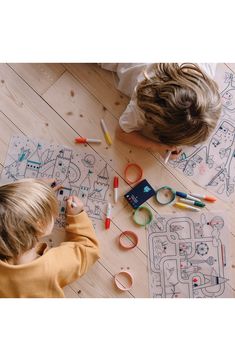 two children are drawing on the floor with crayons