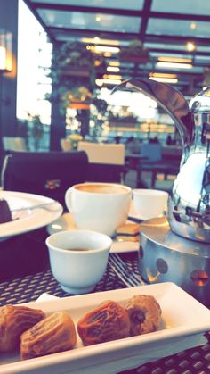 some food is sitting on a table with cups and saucers in front of it