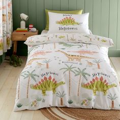 a bed with dinosaurs and palm trees on it