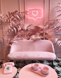 a pink couch sitting next to a table with two cups and a phone on it