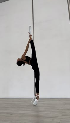 a woman standing on one leg and holding onto a pole with her hands in the air