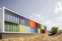 a multicolored building on the side of a hill with grass and trees around it