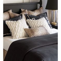 a black and white bed topped with pillows next to a night stand filled with lamps