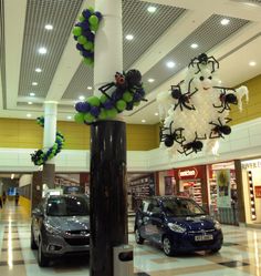 an indoor shopping mall with cars parked in front of it and decorations hanging from the ceiling