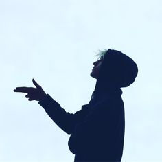 the silhouette of a person holding out their hand in front of a white sky background