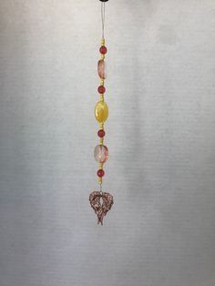 a wind chime hanging from the side of a white wall with beads and charms attached to it