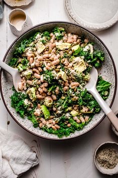 a bowl filled with beans, broccoli and other food on top of a table