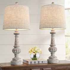 two lamps sitting on top of a table next to a vase with flowers in it