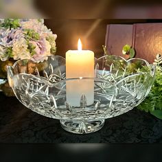 a lit candle sitting in a glass bowl on a table with flowers and other decorations