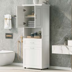 a bathroom with marble walls and flooring, including a white cabinet next to a toilet