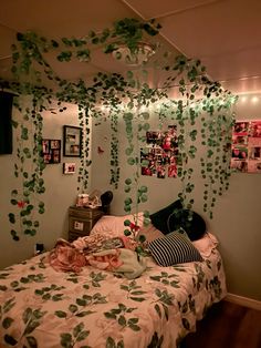 a bedroom decorated in green and white with hanging plants on the wall above the bed