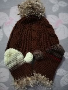 a brown knitted hat with two pom poms