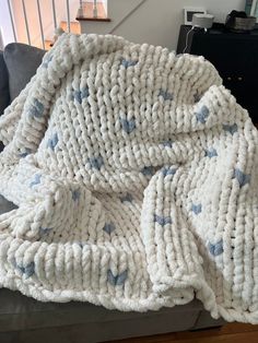 a white blanket with blue hearts on it sitting on top of a couch next to a stair case